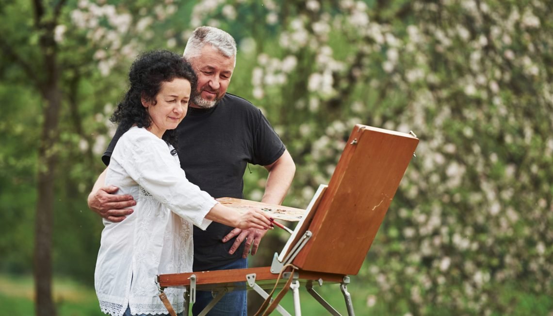 Attention to details. Mature couple have leisure days and working on the paint together in the park.